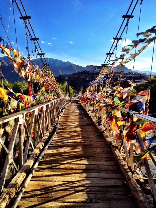 A wooden bridge over the Indus river with Stakna monastery in the background